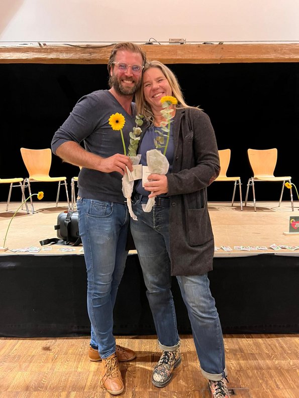 Das Vorstands-Duo Benjamin Barho und Elke Schubert (v.li.) mit Blumen in der Hand vor der Bühne im Pfarrstadel in Weßling